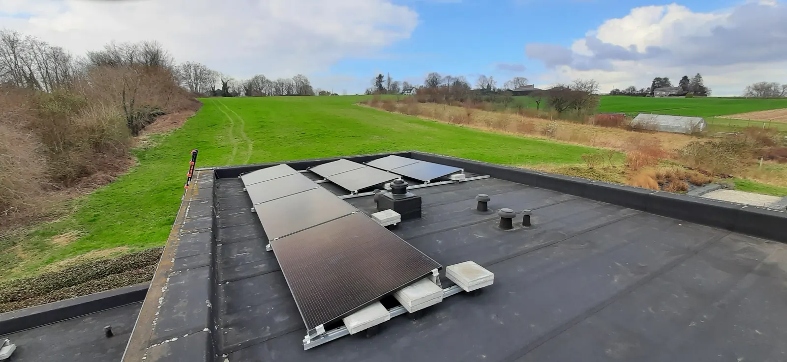 Zonnepanelen op een plat dak met zicht op het landschap